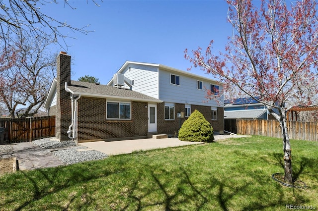 9562 W Capri Dr, Littleton, CO 80123 - back of property with a chimney, a patio area, brick siding, fence, and a lawn