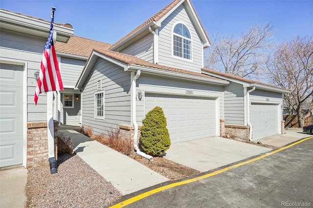 view of front of home featuring a garage, brick siding, and a tiled roof