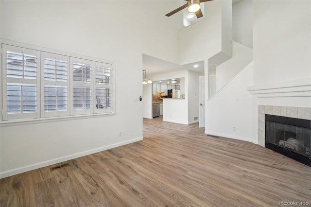 unfurnished living room featuring baseboards, visible vents, ceiling fan, and a tiled fireplace