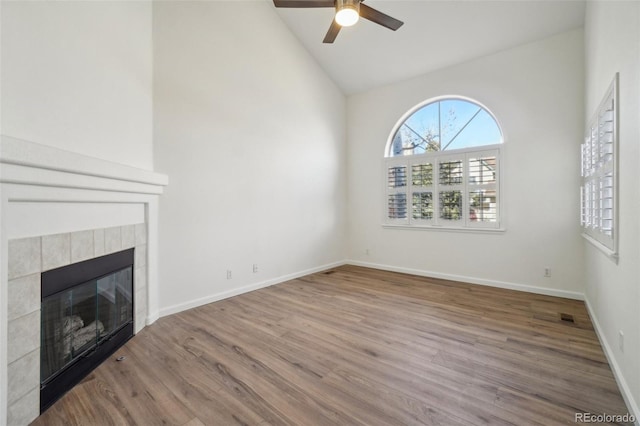 unfurnished living room featuring a tile fireplace, wood finished floors, a ceiling fan, visible vents, and baseboards