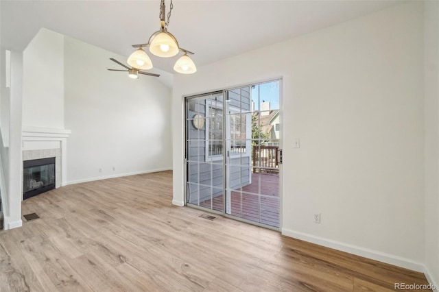 unfurnished living room featuring baseboards, a tiled fireplace, and wood finished floors