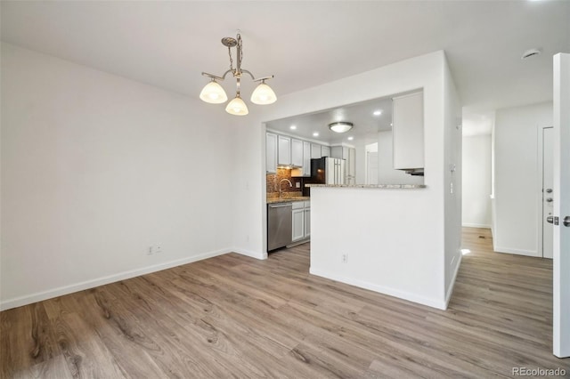 kitchen featuring tasteful backsplash, freestanding refrigerator, light wood-style floors, and stainless steel dishwasher