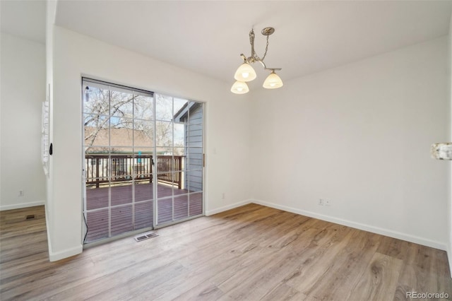 unfurnished dining area featuring a chandelier, visible vents, baseboards, and wood finished floors