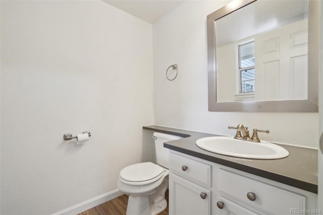 bathroom with wood finished floors, vanity, toilet, and baseboards