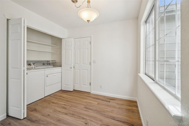 laundry area featuring laundry area, wood finished floors, washing machine and clothes dryer, and baseboards