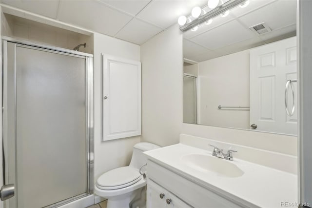 full bathroom featuring toilet, a paneled ceiling, vanity, visible vents, and a shower stall