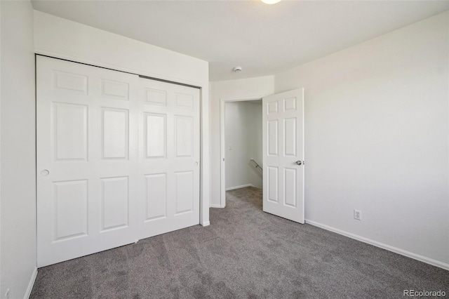 unfurnished bedroom with carpet floors, baseboards, and a closet