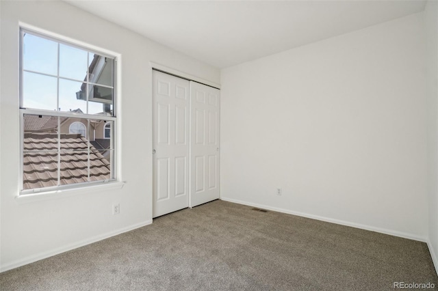 unfurnished bedroom with carpet, a closet, visible vents, and baseboards