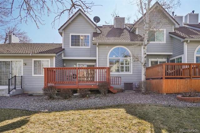 rear view of property with a deck, a chimney, a lawn, and central air condition unit