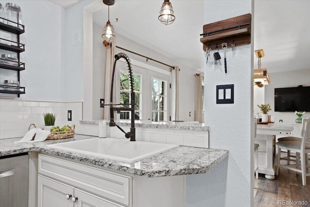kitchen featuring dark wood-style flooring, dishwasher, white cabinets, backsplash, and decorative light fixtures