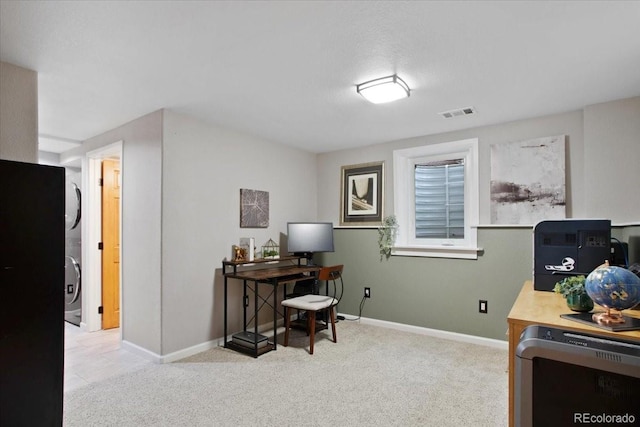 home office with stacked washing maching and dryer, baseboards, carpet, and visible vents