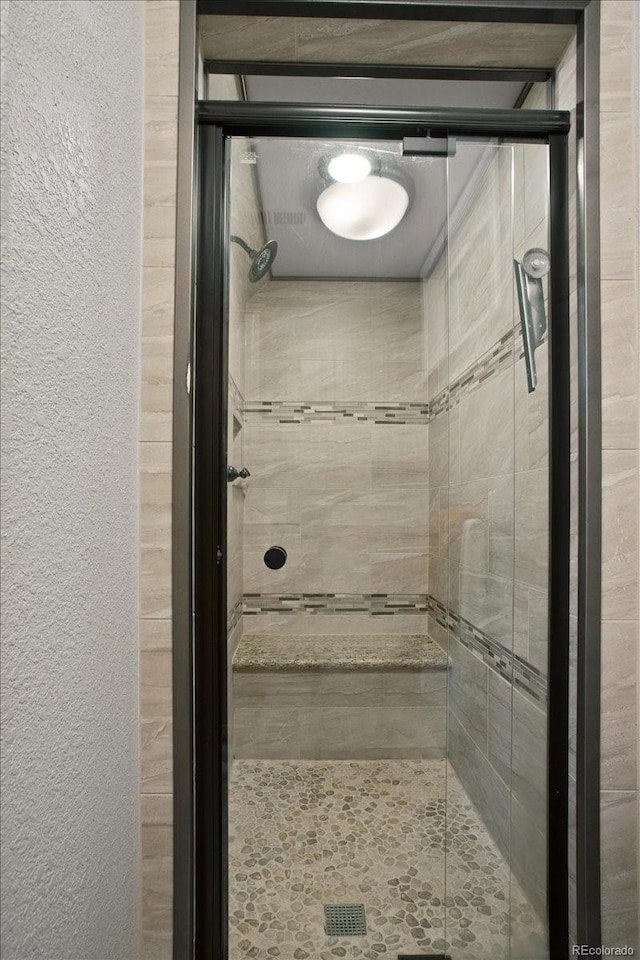 bathroom featuring a textured wall and a shower stall