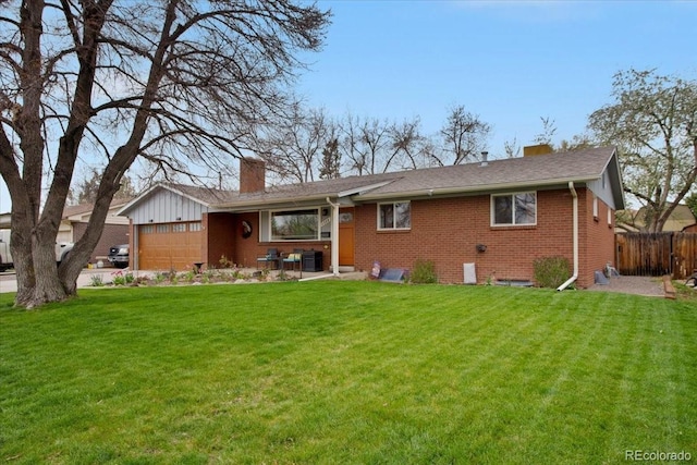 view of front of home featuring a chimney, a front yard, brick siding, fence, and an attached garage