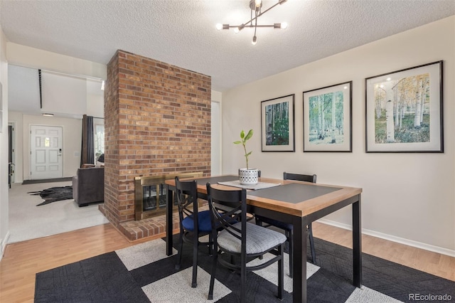 8039 E Phillips Cir, Centennial, CO 80112 - dining space with wood finished floors, a textured ceiling, a chandelier, and a fireplace