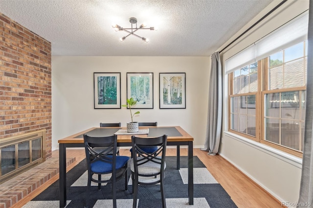 8039 E Phillips Cir, Centennial, CO 80112 - dining area with a textured ceiling, light wood-style flooring, a chandelier, and a fireplace