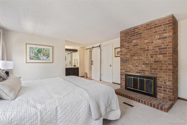 8039 E Phillips Cir, Centennial, CO 80112 - bedroom featuring a barn door, carpet, a textured ceiling, a fireplace, and ensuite bathroom