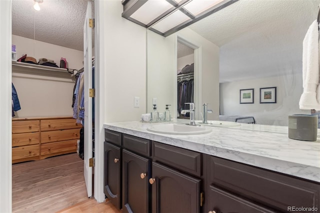 8039 E Phillips Cir, Centennial, CO 80112 - full bath featuring a textured ceiling, vanity, a spacious closet, and wood finished floors