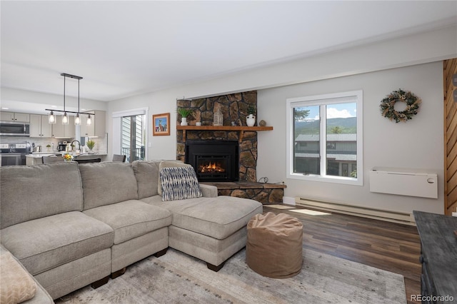 141 Forest Trl # 16, Winter Park, CO 80482 - living room featuring a baseboard radiator, light wood finished floors, a stone fireplace, and healthy amount of natural light