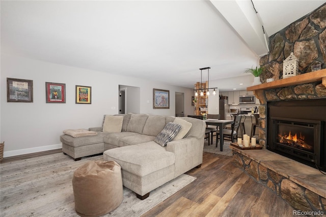 141 Forest Trl # 16, Winter Park, CO 80482 - living room featuring wood finished floors, a stone fireplace, and a chandelier