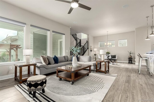 21492 E 60th Ave, Aurora, CO 80019 - living area with baseboards, stairway, light wood-type flooring, and ceiling fan with notable chandelier