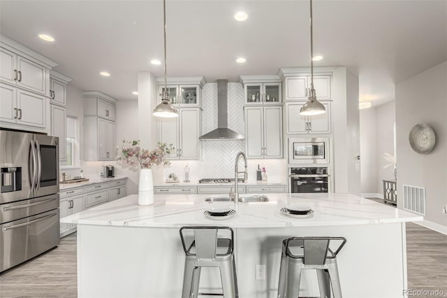 21492 E 60th Ave, Aurora, CO 80019 - kitchen featuring a sink, stainless steel appliances, visible vents, wall chimney exhaust hood, and light wood-style floors