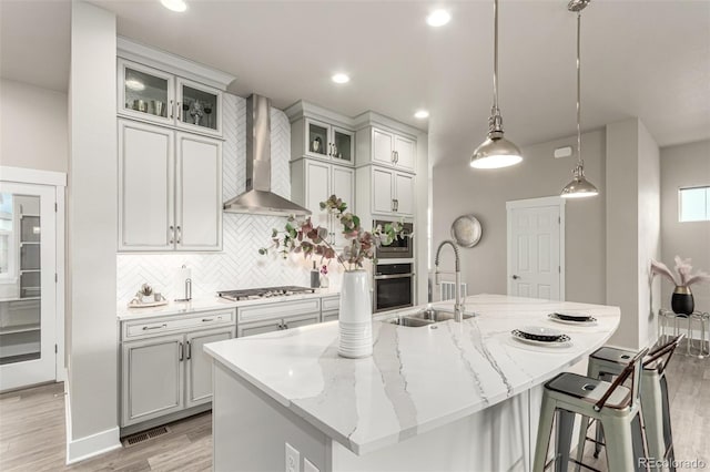 21492 E 60th Ave, Aurora, CO 80019 - kitchen featuring light wood-style flooring, a sink, wall chimney range hood, stainless steel gas stovetop, and tasteful backsplash