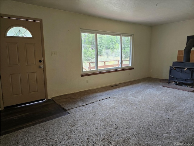 2793 S Beaver Creek Rd, Black Hawk, CO 80422 - unfurnished living room featuring a wood stove, carpet, and baseboards