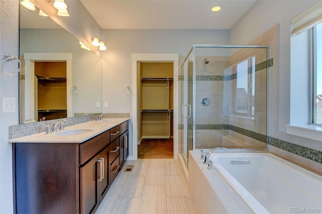 bathroom featuring a bath, a spacious closet, and a sink