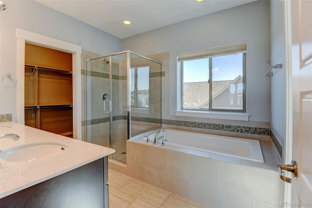 bathroom with a stall shower, a spacious closet, a bath, and vanity