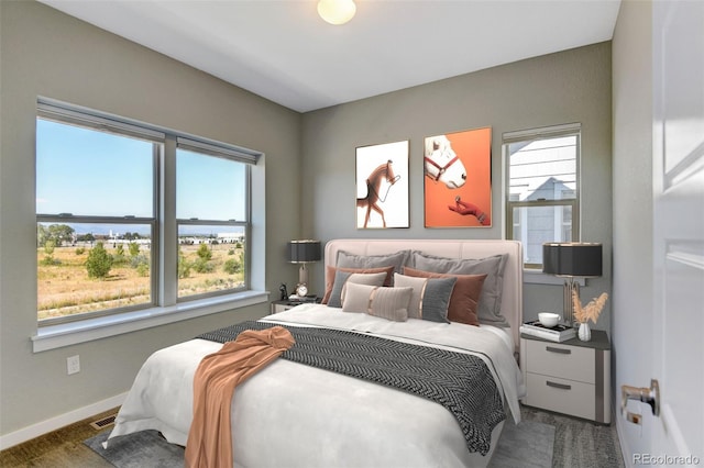 bedroom featuring multiple windows, a water view, visible vents, and baseboards