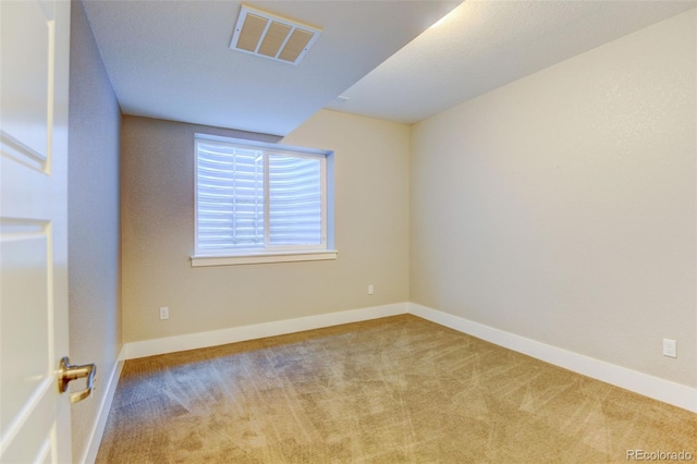 empty room featuring baseboards, visible vents, and light colored carpet