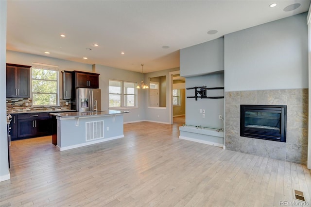 kitchen with a breakfast bar, pendant lighting, open floor plan, a kitchen island, and stainless steel fridge