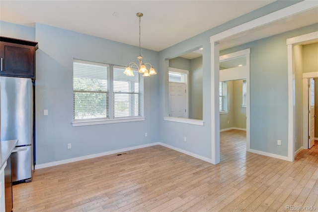 interior space featuring light wood-style floors, a chandelier, visible vents, and baseboards