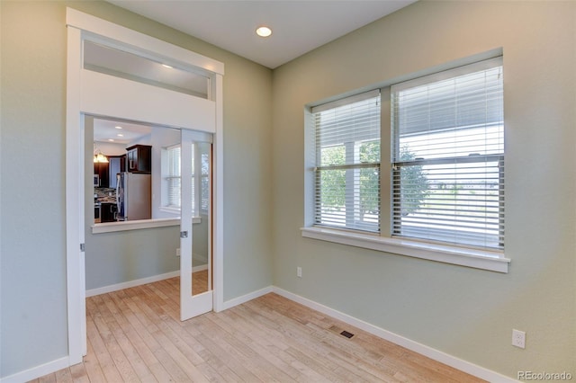 unfurnished room with recessed lighting, visible vents, light wood-style flooring, and baseboards