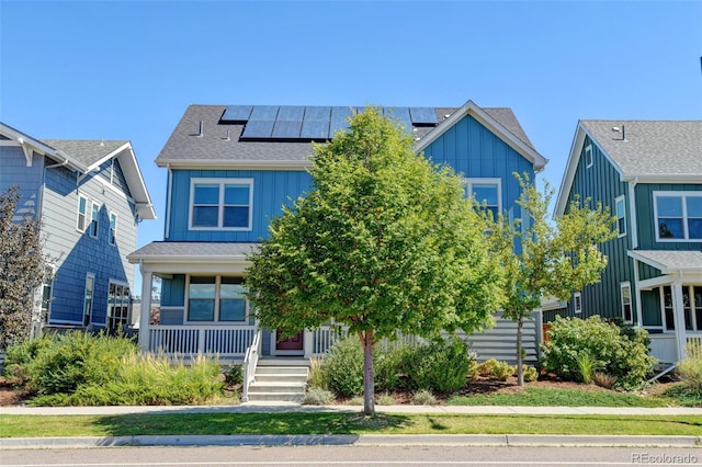 view of front of home featuring solar panels, a porch, board and batten siding, and a shingled roof