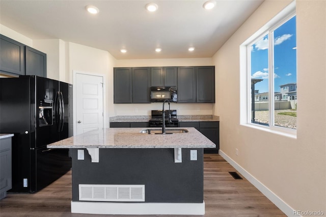 9805 Granite Park Ln, Peyton, CO 80831 - kitchen featuring black appliances, light stone counters, a breakfast bar, a kitchen island with sink, and recessed lighting
