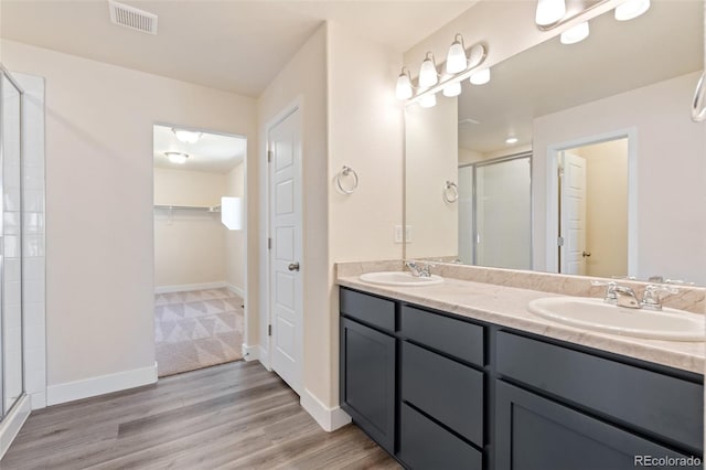 9805 Granite Park Ln, Peyton, CO 80831 - bathroom with a stall shower, a walk in closet, double vanity, and wood finished floors