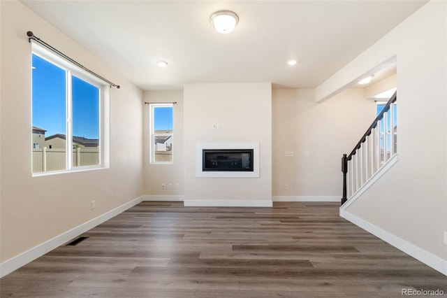 9805 Granite Park Ln, Peyton, CO 80831 - unfurnished living room featuring wood finished floors, a glass covered fireplace, recessed lighting, and stairs