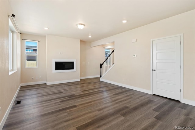 9805 Granite Park Ln, Peyton, CO 80831 - unfurnished living room featuring stairway, dark wood-style floors, a glass covered fireplace, and recessed lighting
