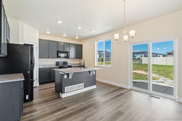 9805 Granite Park Ln, Peyton, CO 80831 - kitchen with black appliances, wood finished floors, a chandelier, recessed lighting, and a breakfast bar area