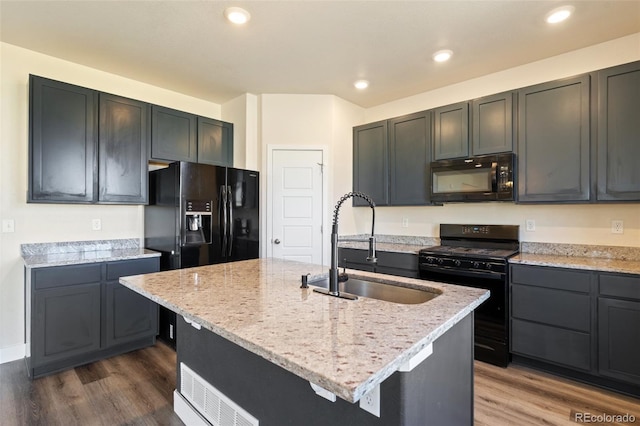 9805 Granite Park Ln, Peyton, CO 80831 - kitchen featuring black appliances, light stone countertops, dark wood finished floors, recessed lighting, and a kitchen island with sink