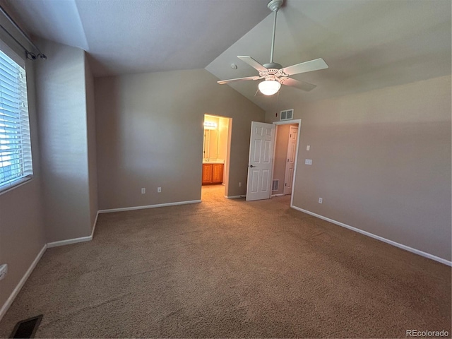 unfurnished bedroom with ceiling fan, ensuite bath, light carpet, and vaulted ceiling