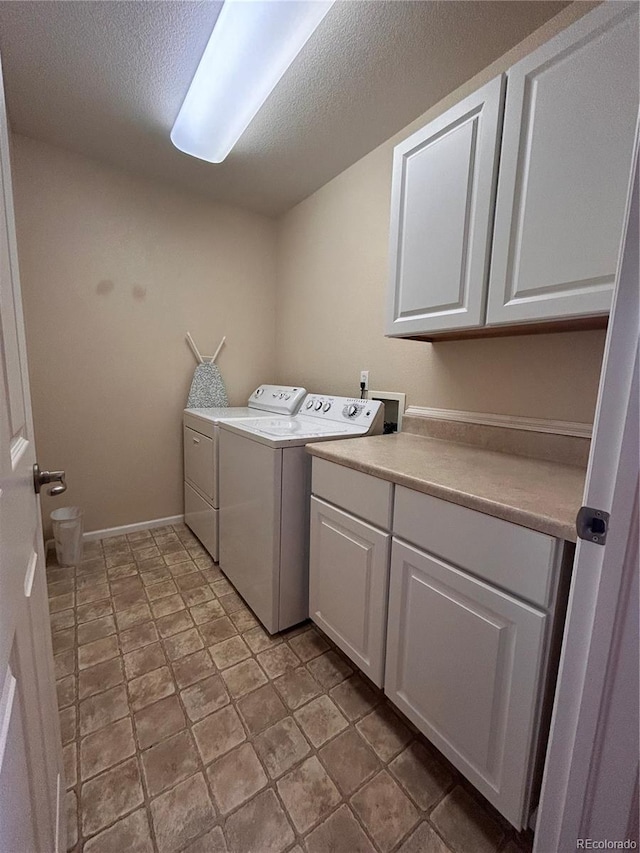 laundry area with cabinets, a textured ceiling, and washer and dryer