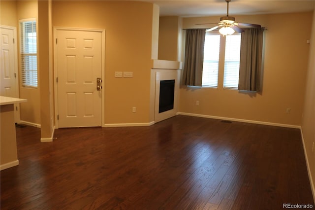 unfurnished living room with ceiling fan and dark wood-type flooring