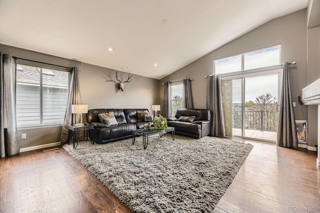 living room featuring vaulted ceiling, wood finished floors, baseboards, recessed lighting, and a fireplace