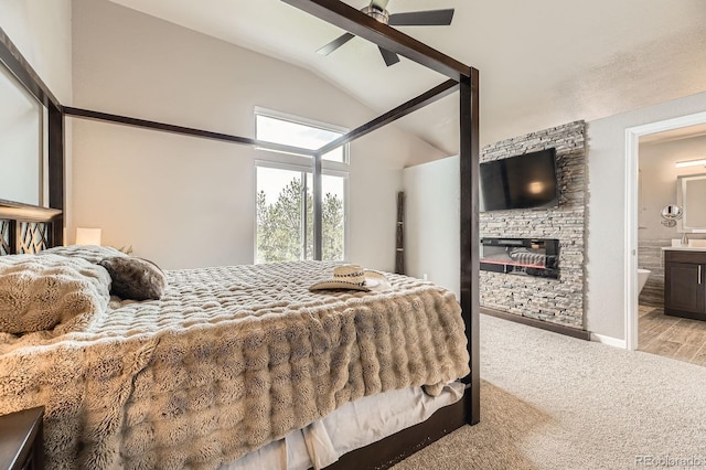 bedroom with vaulted ceiling, a fireplace, carpet flooring, and connected bathroom