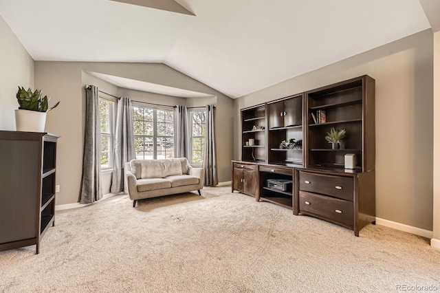 office space featuring vaulted ceiling, light colored carpet, and baseboards