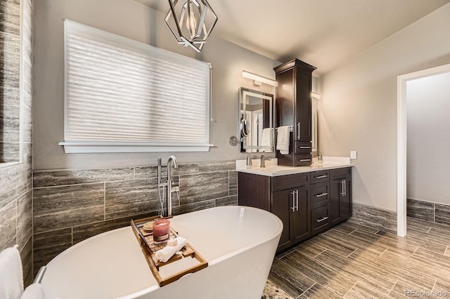 full bathroom featuring tile walls, a soaking tub, double vanity, and wood finish floors