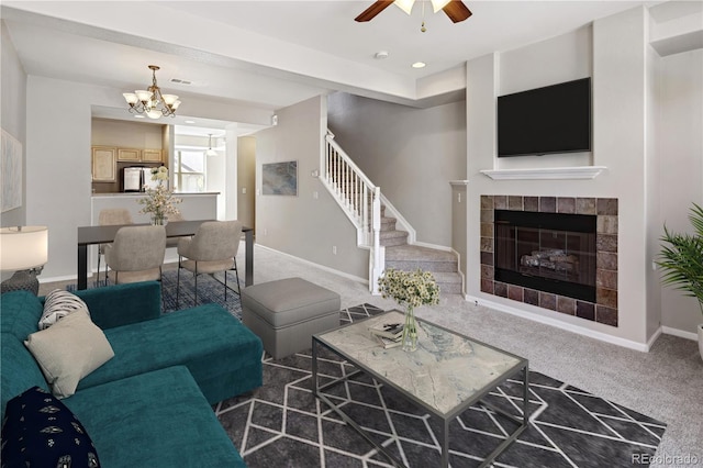 carpeted living room with ceiling fan with notable chandelier and a fireplace