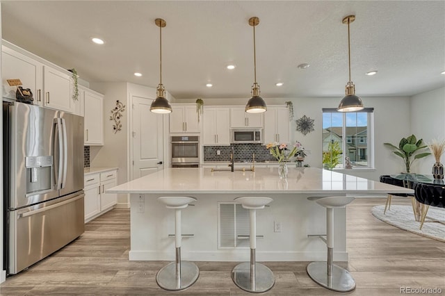 17194 Desert Wine Ln, Parker, CO 80134 - kitchen with appliances with stainless steel finishes, light wood-style floors, decorative backsplash, recessed lighting, and white cabinetry